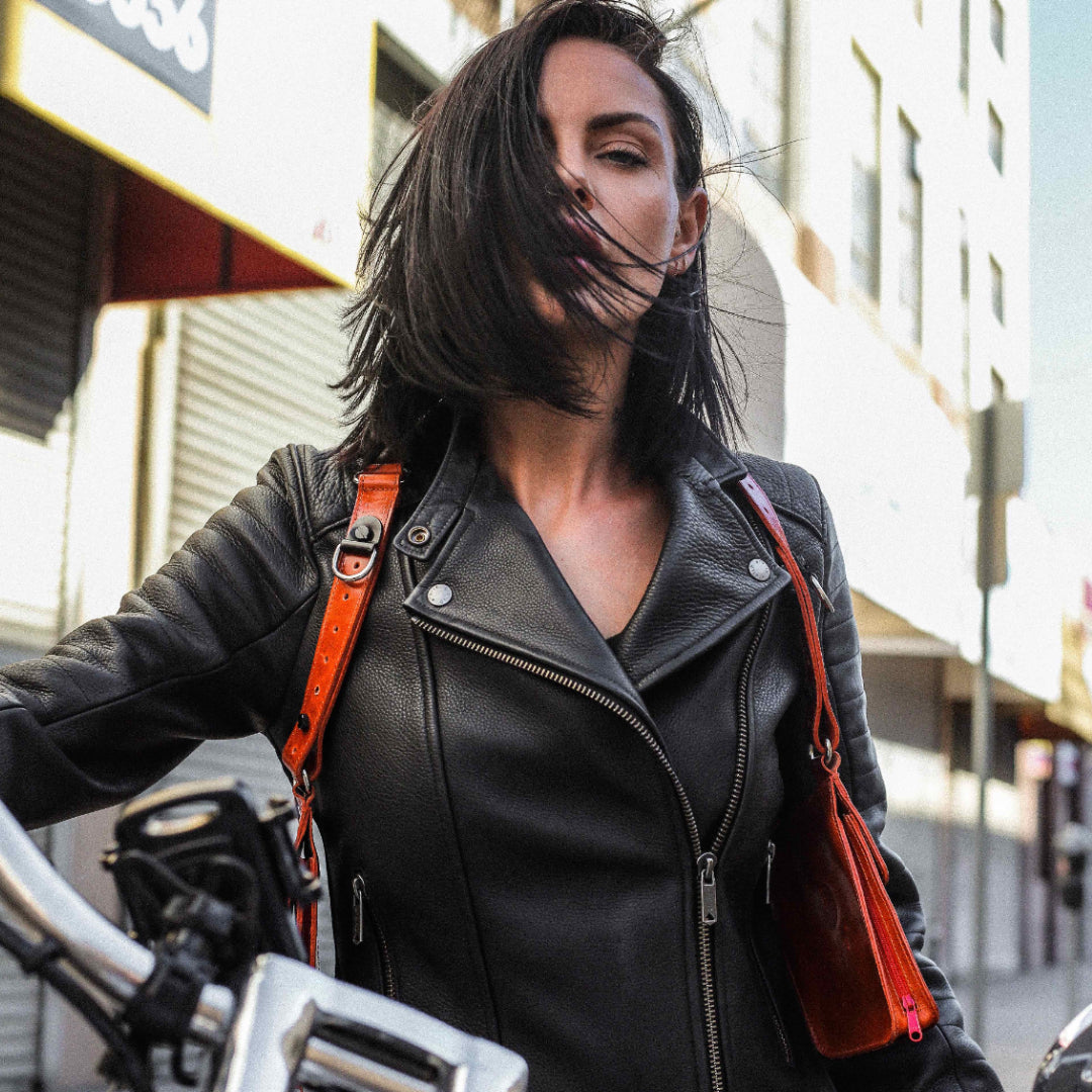 Teela La Roux wearing the NiK Kacy Modular Leather Holster in Tiger Orange, demonstrating hands-free convenience, ergonomic fit, and modern unisex styling. (Dual holster bag shown)